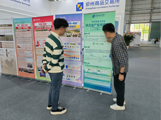 （图注：郑商所展台工作人员介绍铁合金产业绿色发展项目）